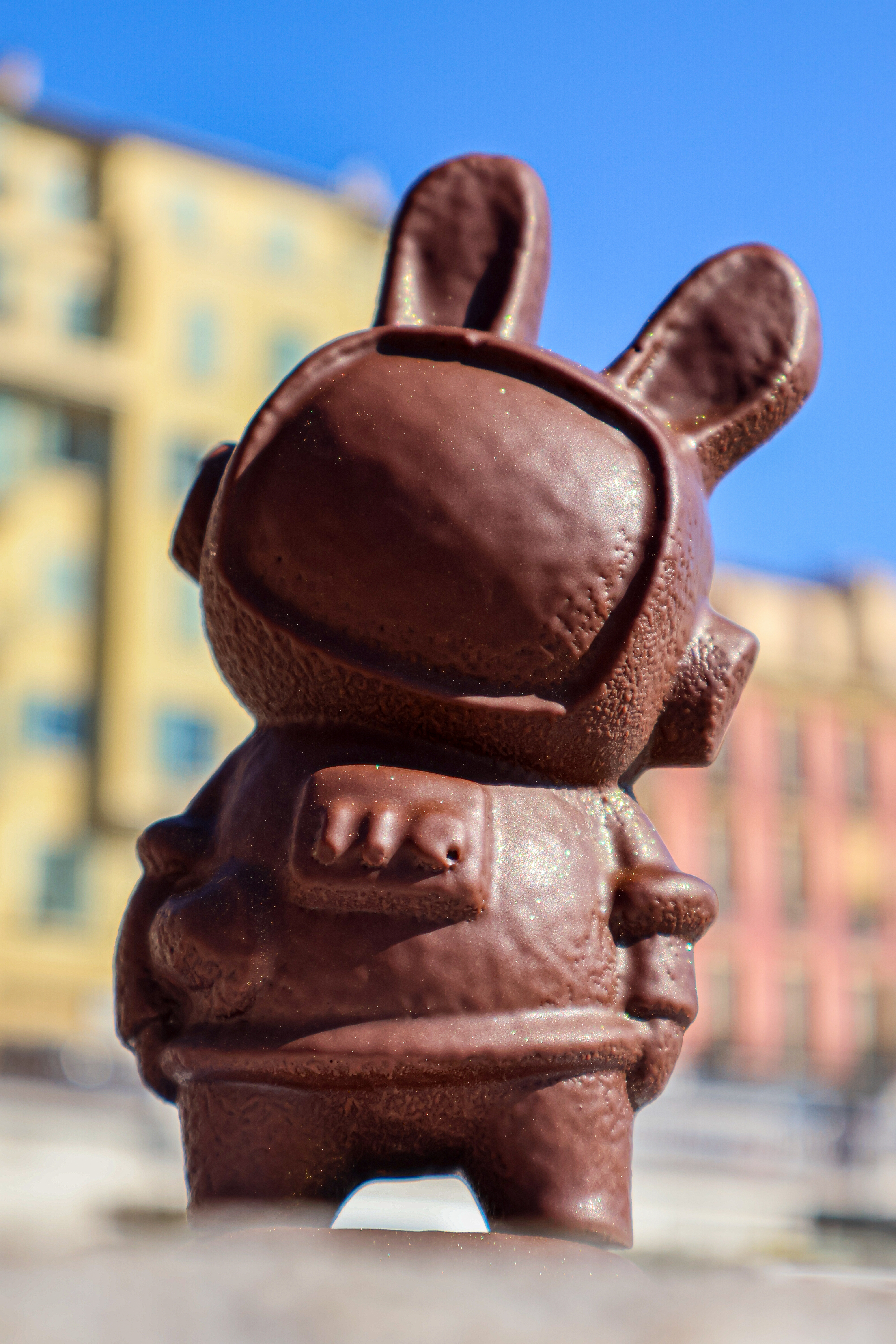 Lapin astronaute en chocolat noir avec bâtiments en arrière plan 