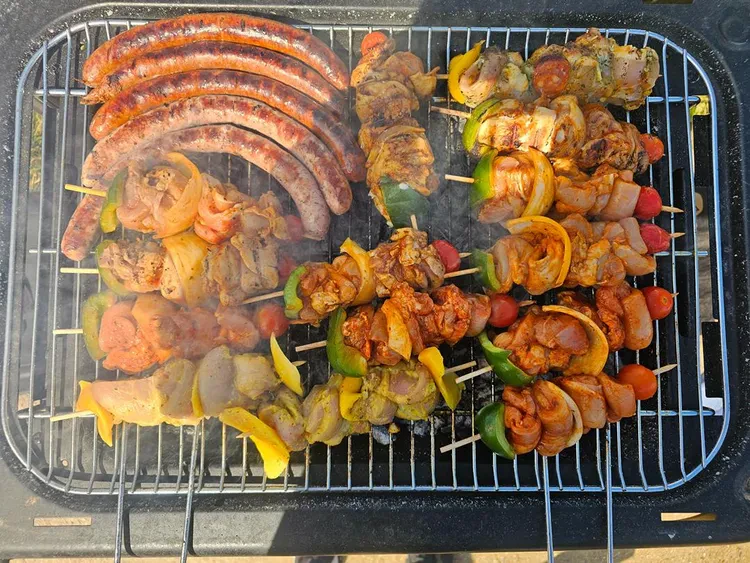 Barbecue avec des brochettes, des saucisses et des merguez