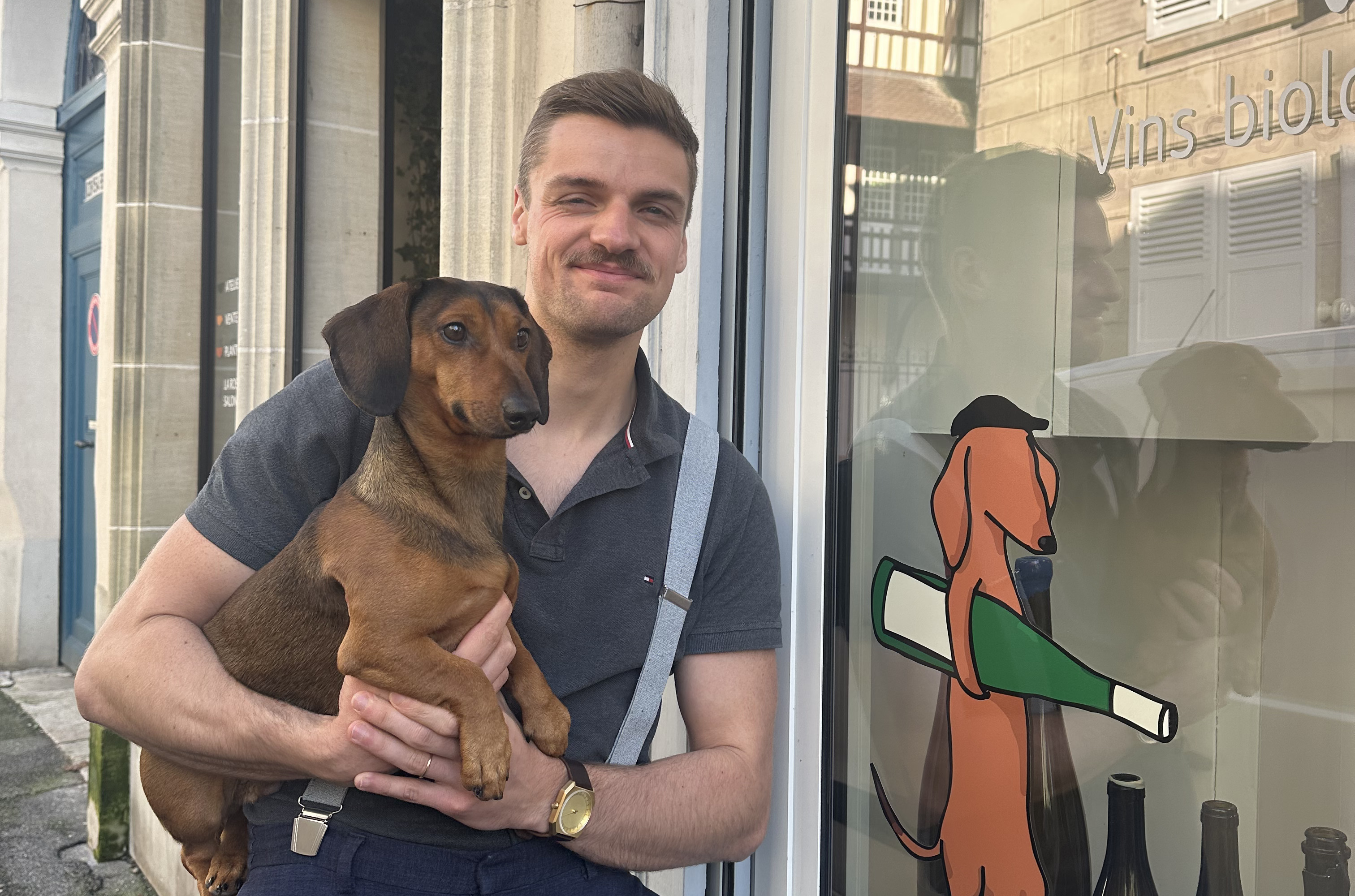 un homme portant un chien devant une vitrine