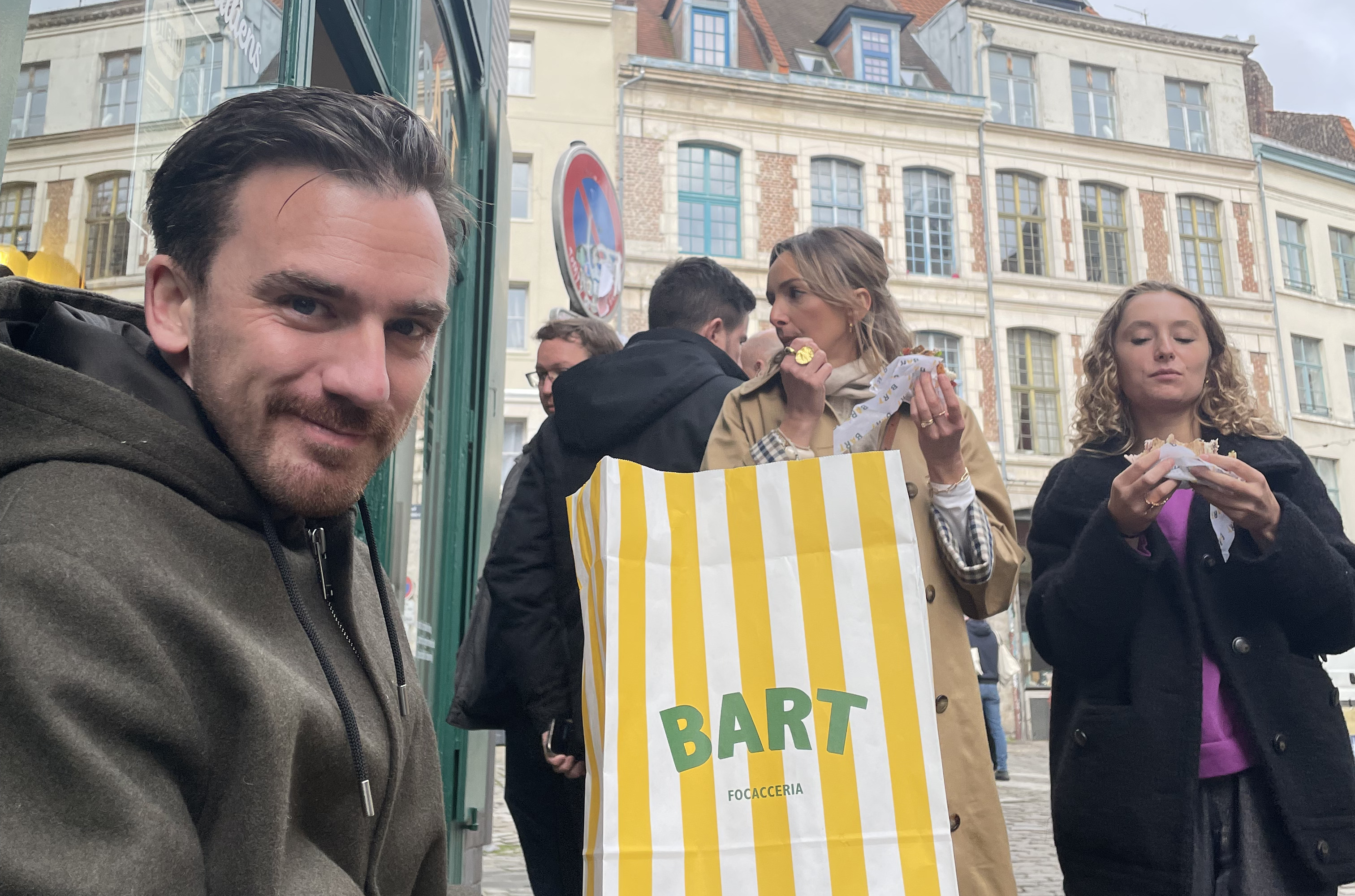 Une personne assis devant un restaurant avec un sac dans les mains