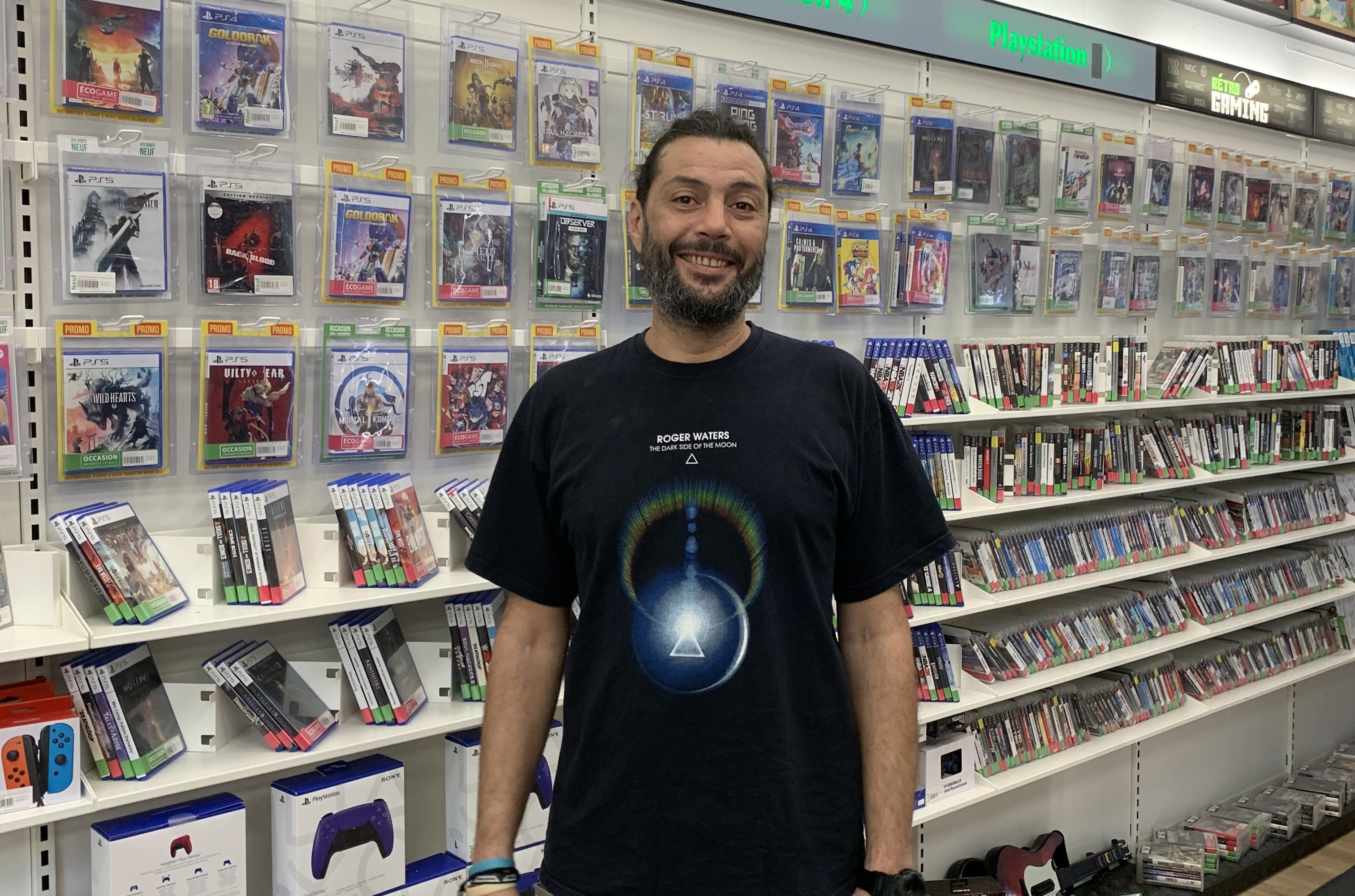 Un homme pose devant des jeux vidéos