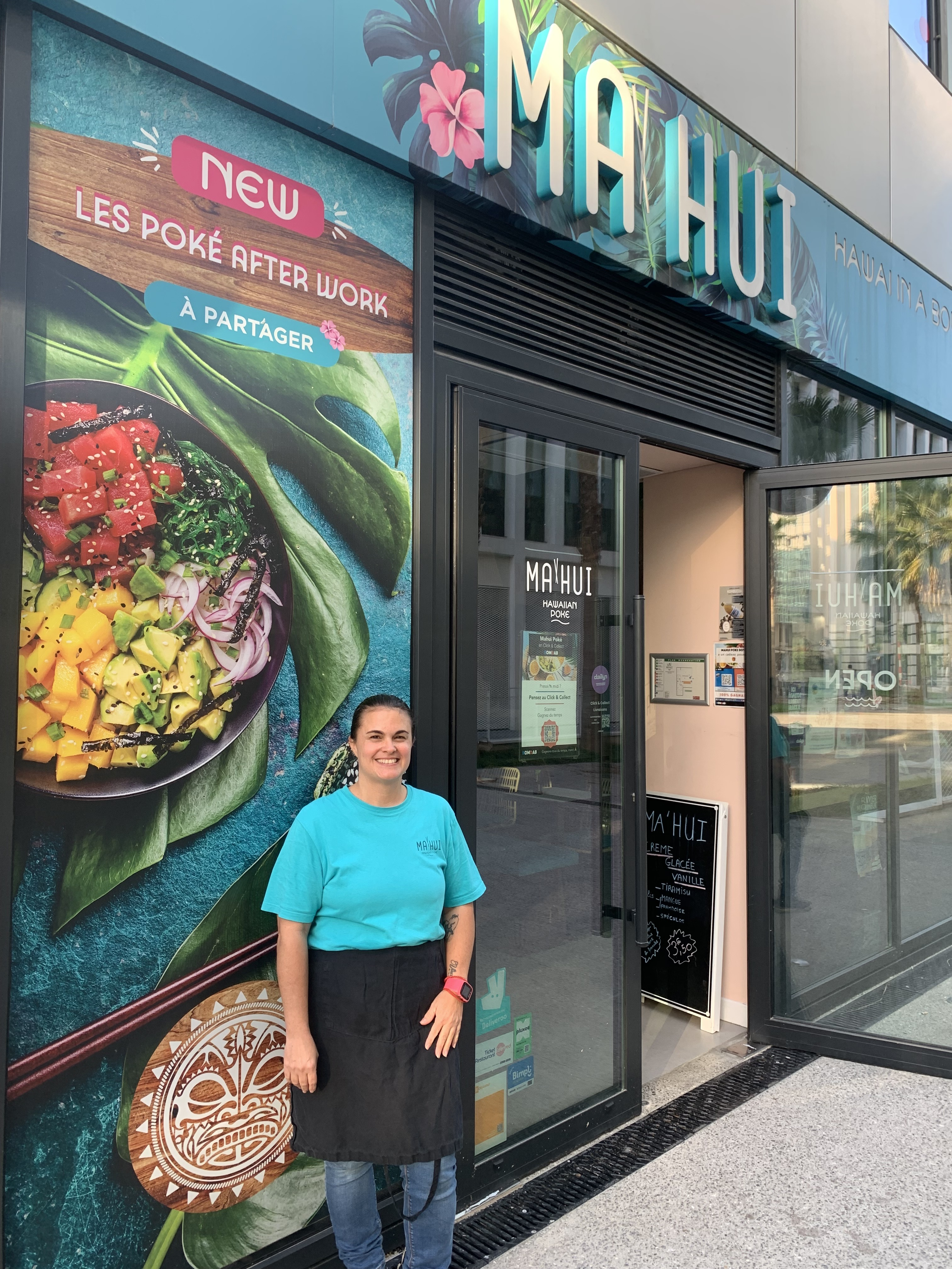 Une femme pose devant un restaurant de poke bowl