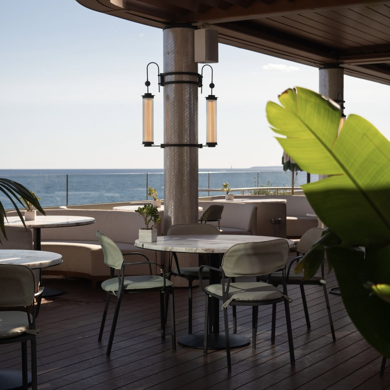 Terasse avec tables et chaises ainsi qu'une vue mer en fond