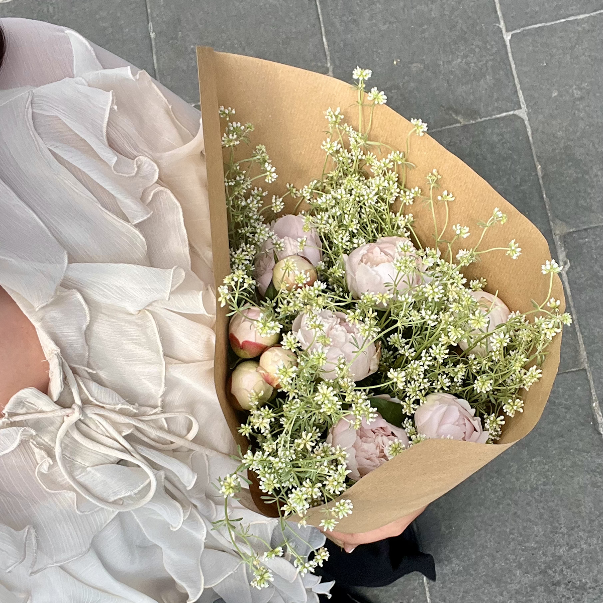 Femme tenant un bouquet de fleurs blanches.