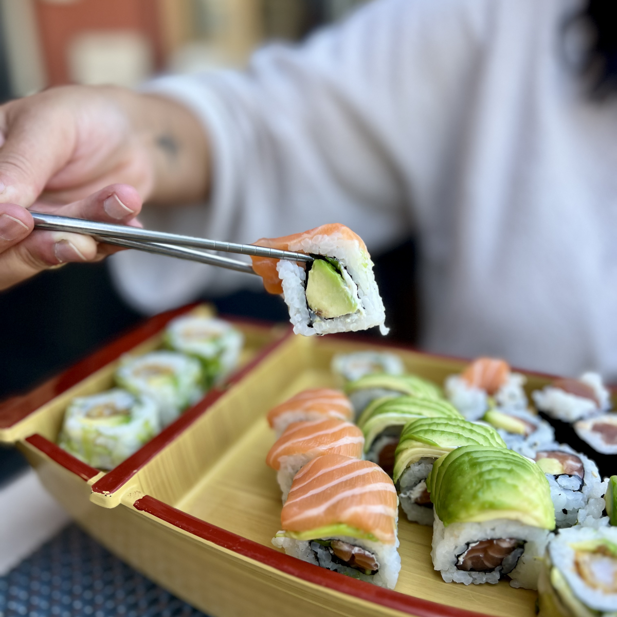 Femme tenant des baguettes avec un sushi