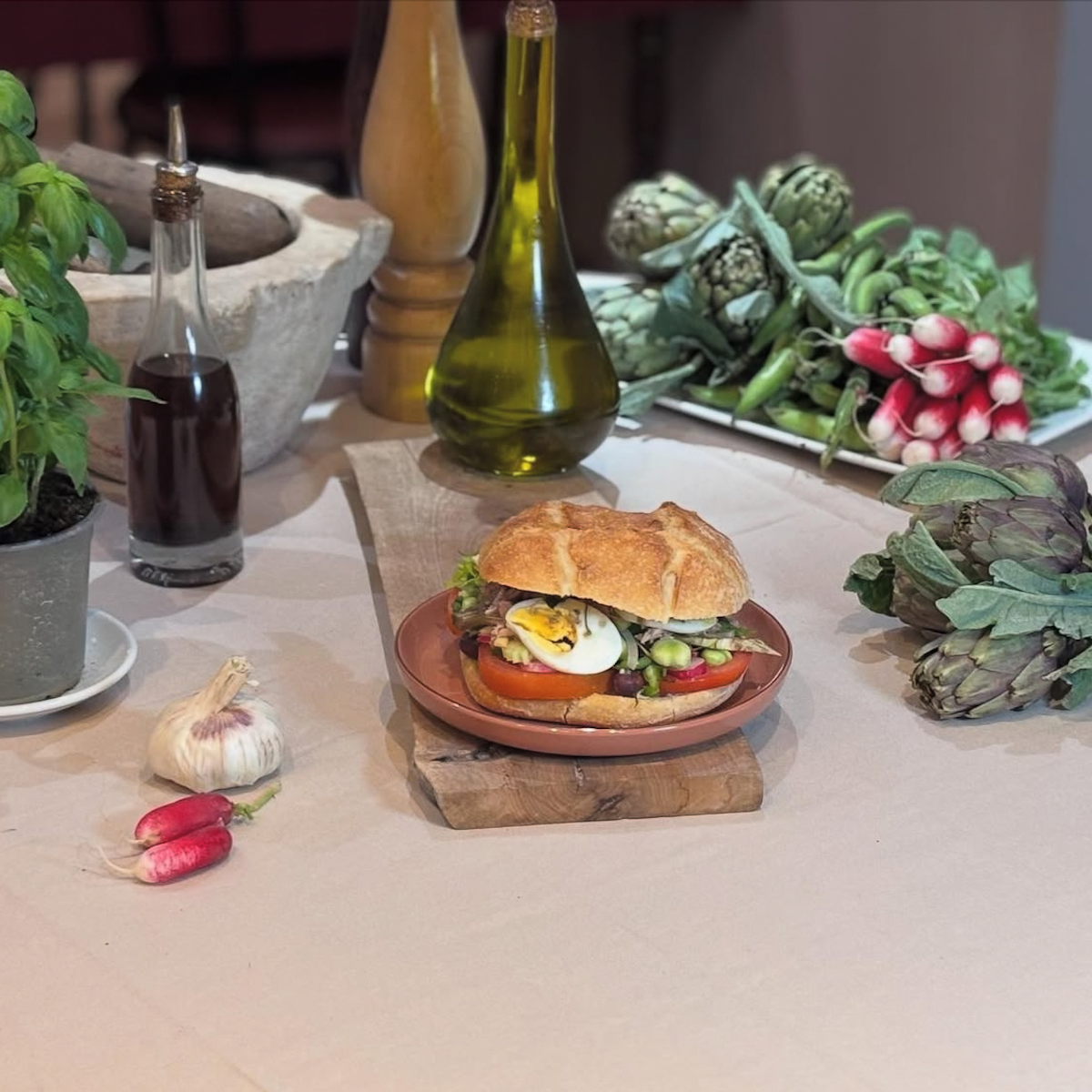 Tables avec un pan bagnat dans une assiette et ingrédients autour.