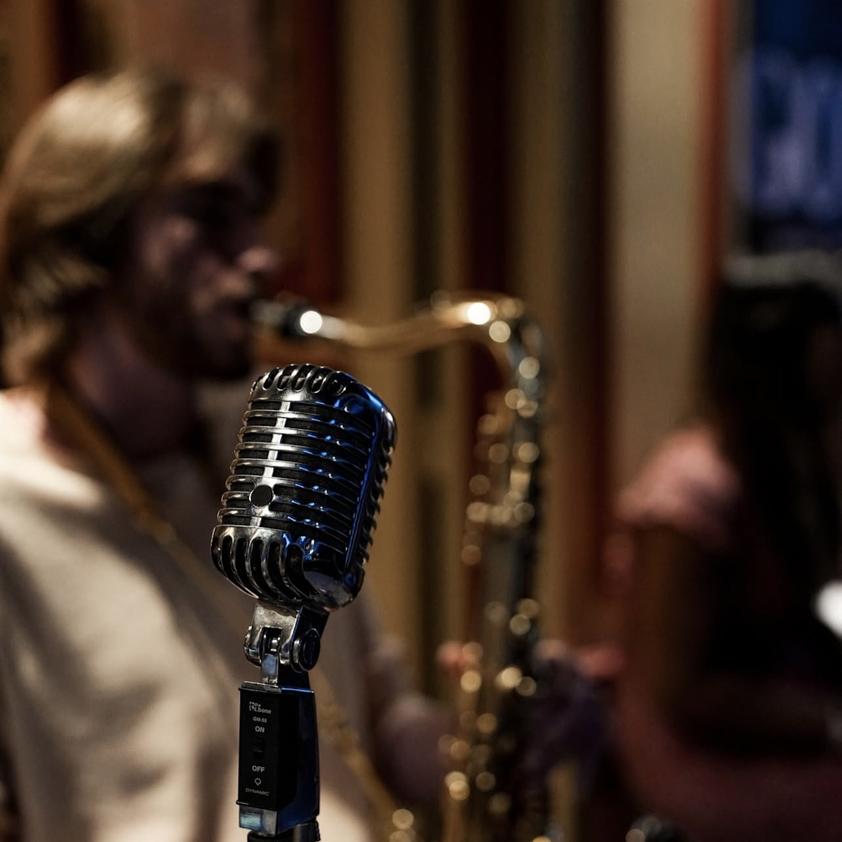 Musicien jouant du saxophone et micro au premier plan