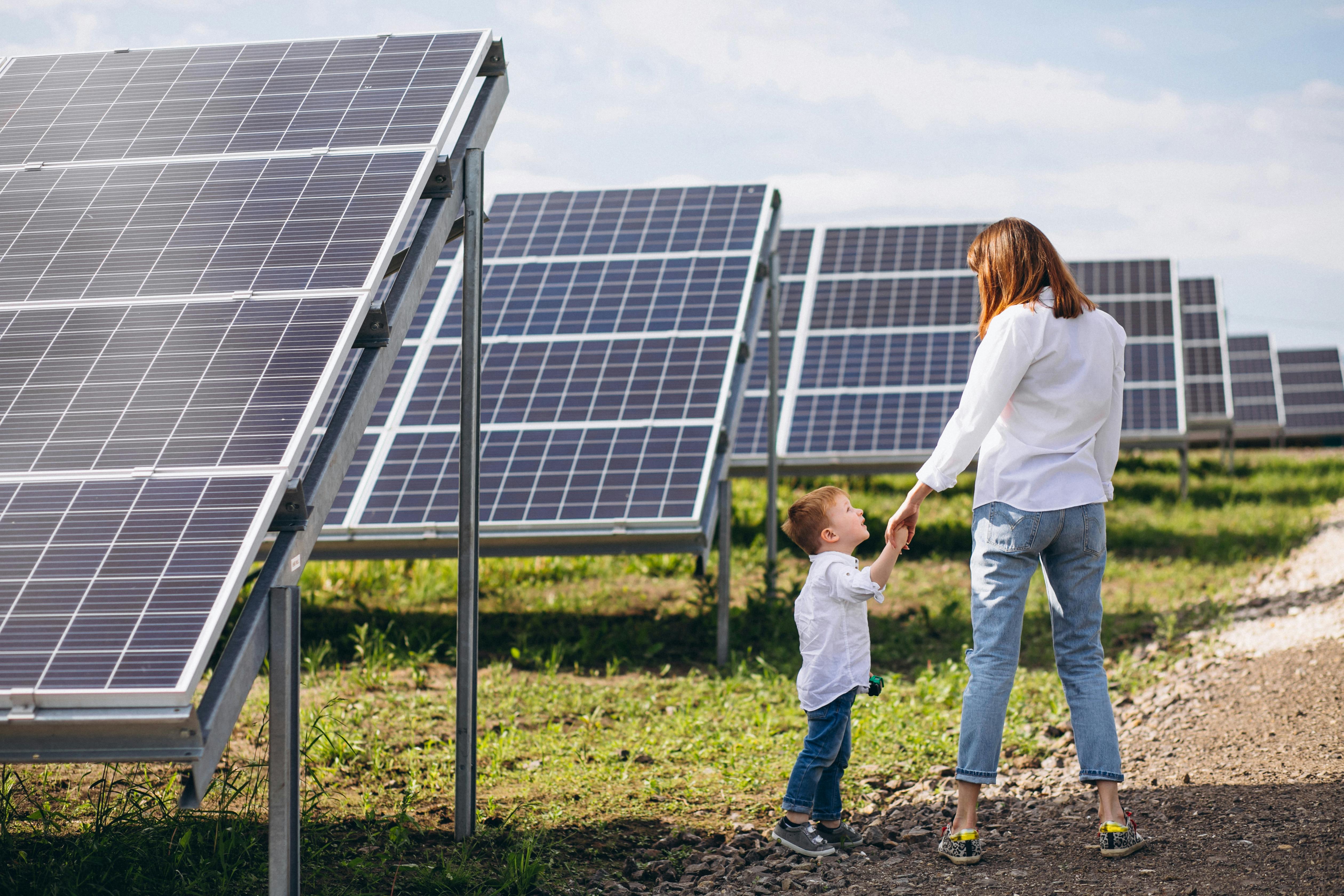 Mãe e filho diante de uma região campestre com algumas placas solares 