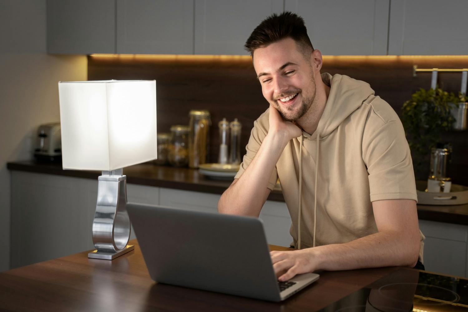 homem sorridente em seu notebook, ambiente caseiro moderno