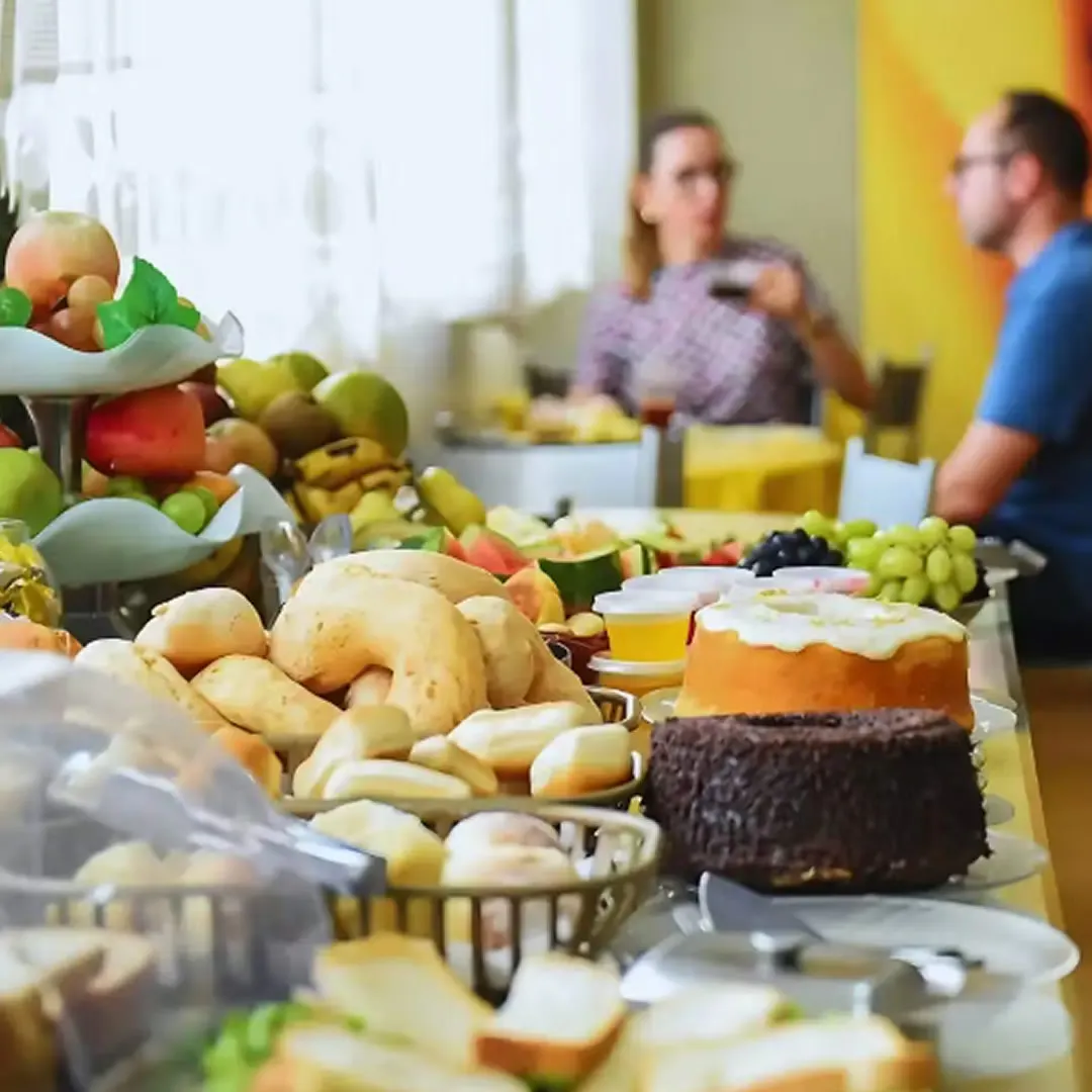 Imagem de um café da manhã servido no Hotel Volp, em Patos de Minas, com diversas opções de alimentos deliciosos e variados, incluindo saladas, queijos e frutas
