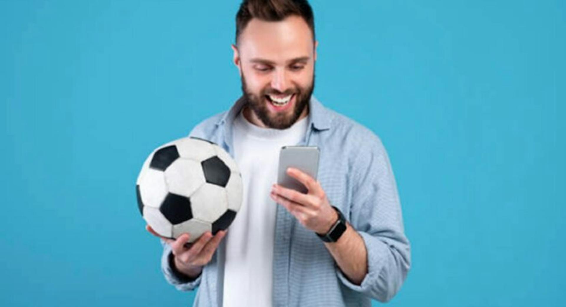 Homem segurando bola de futebol e celular