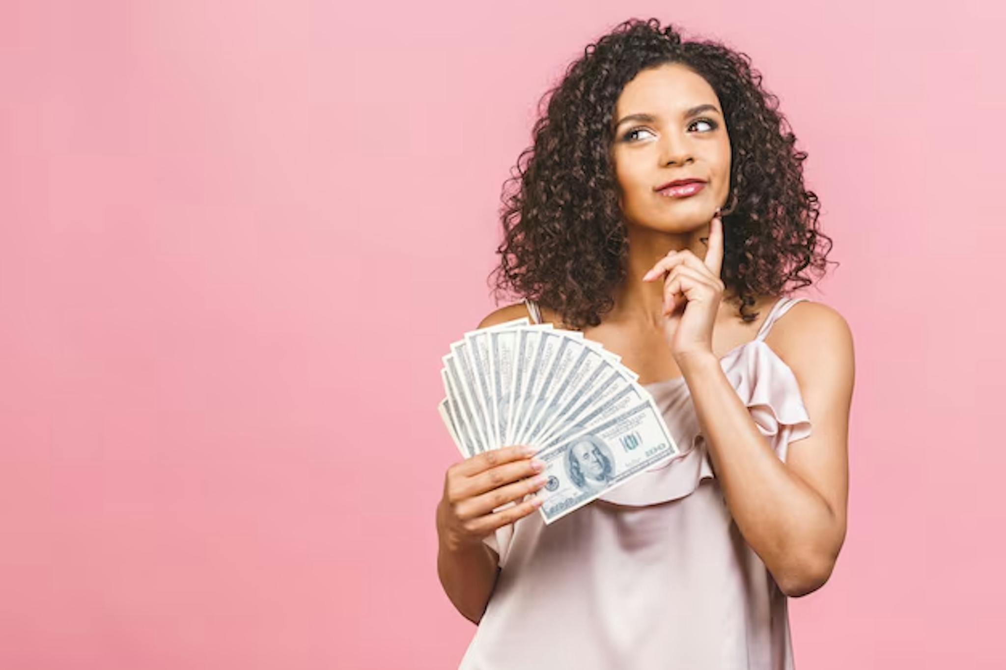 Young woman thinking while holding money