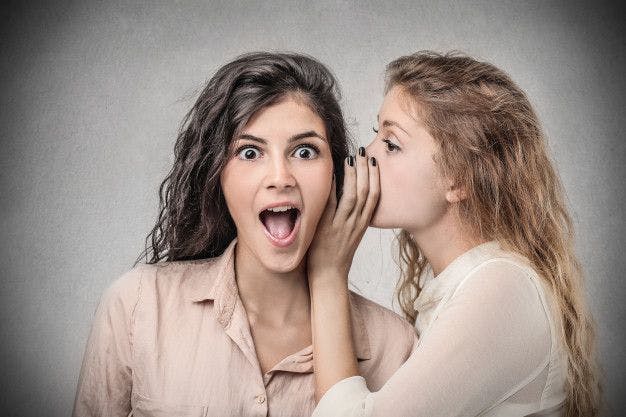 Woman whispering in another woman's ear