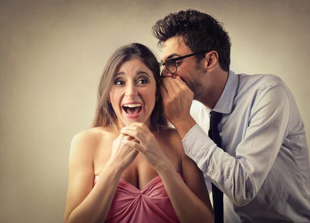 Man whispering in woman's ear