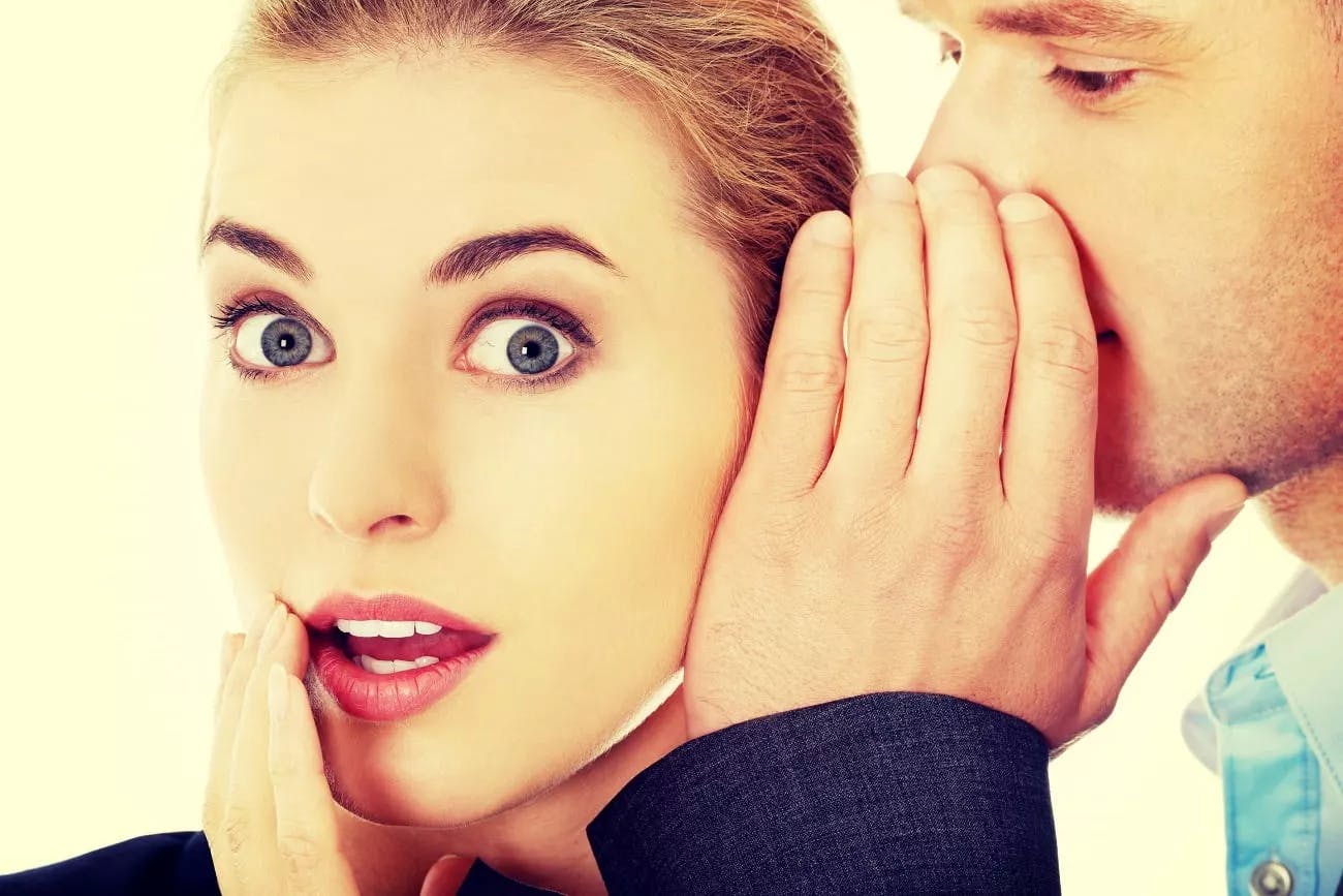 Man whispering in woman's ear