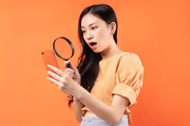 Mujer mirando el teléfono móvil con una lupa