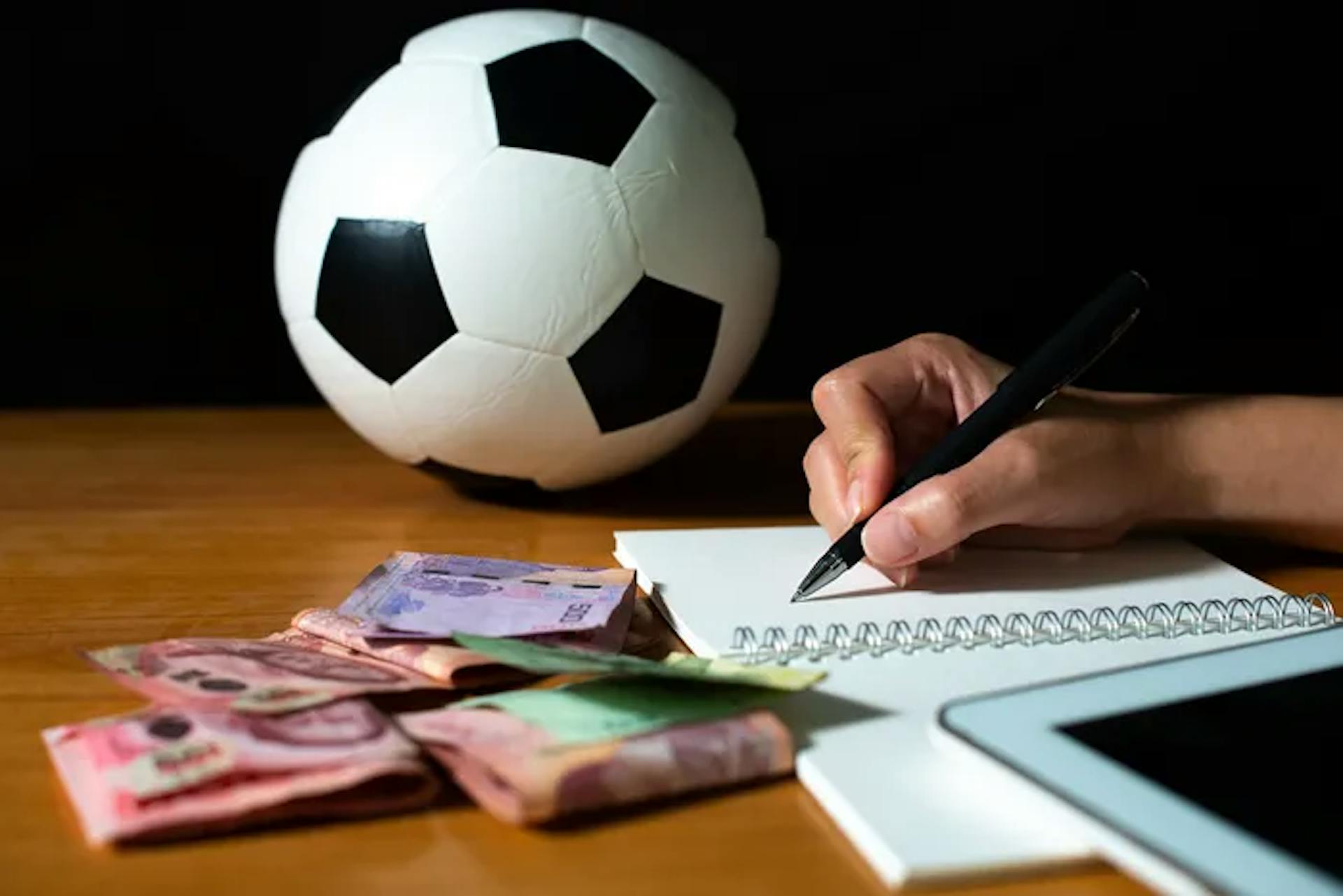 Person writing, football, and money