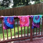 Camisetas Tie Dye penduradas em uma cerca de madeira