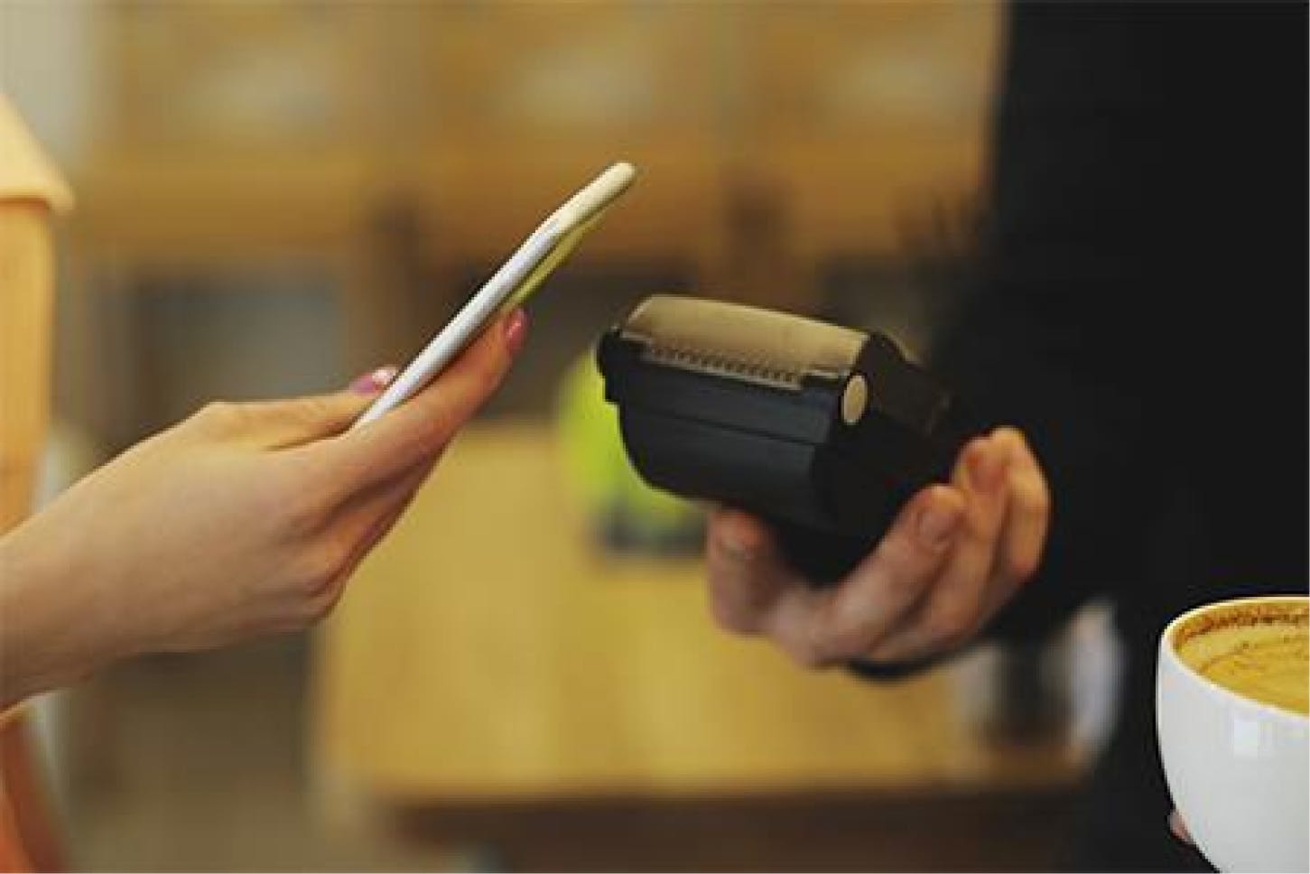 pessoa passando pagamento via leitura de aproximação na máquina de cartão com celular.