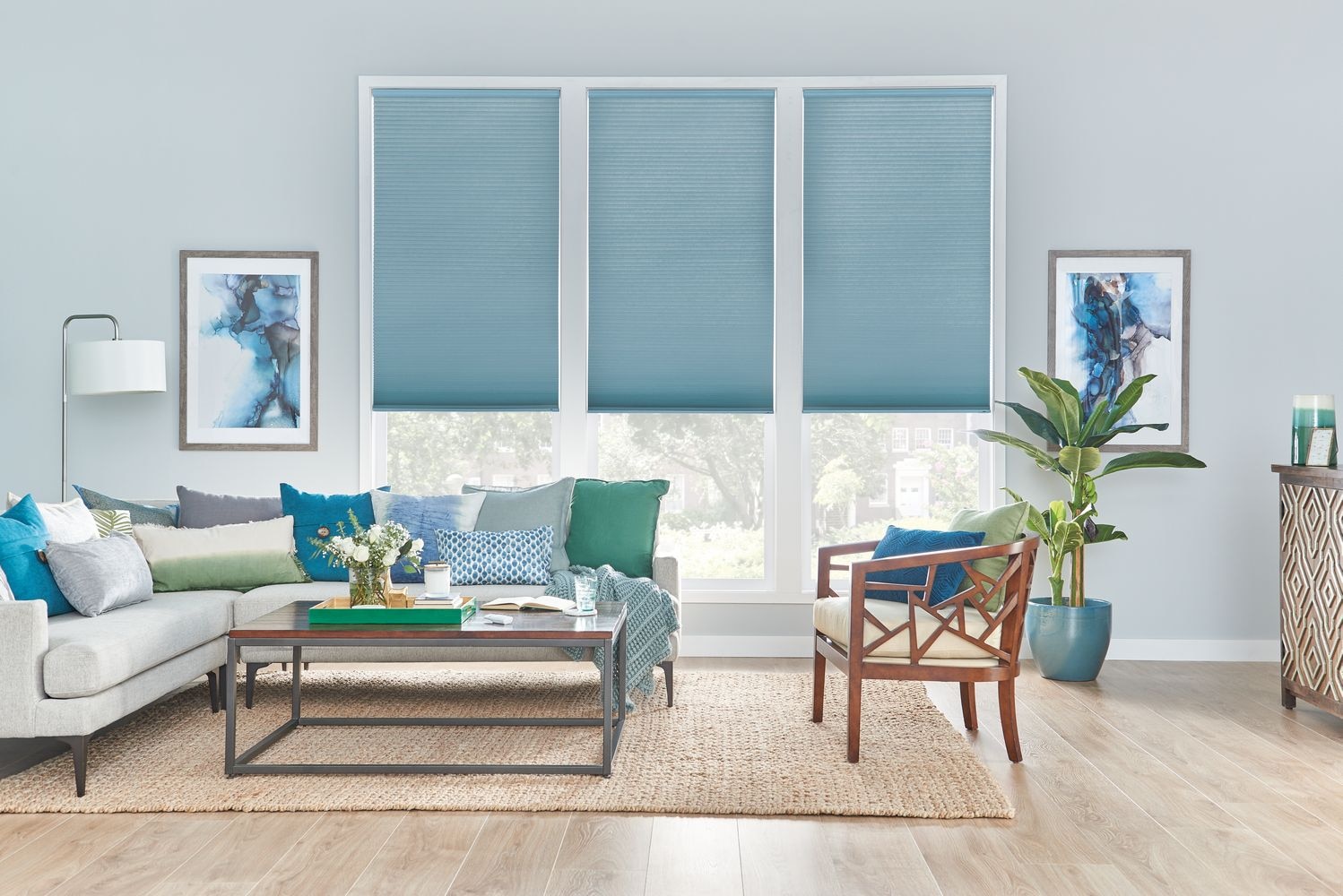 A living room with pastel blue walls and teal cellular shades.