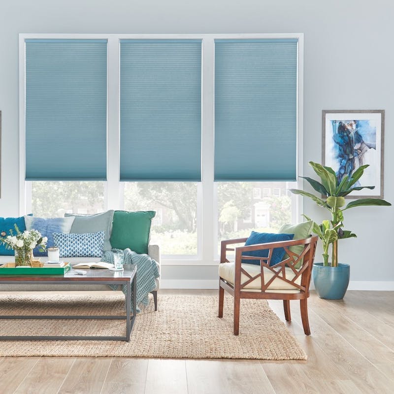 A living room with pastel blue walls and teal cellular shades.