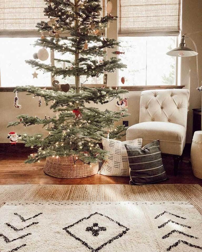 living room decorated for christmas with bank of windows covered with tan linen roman shades