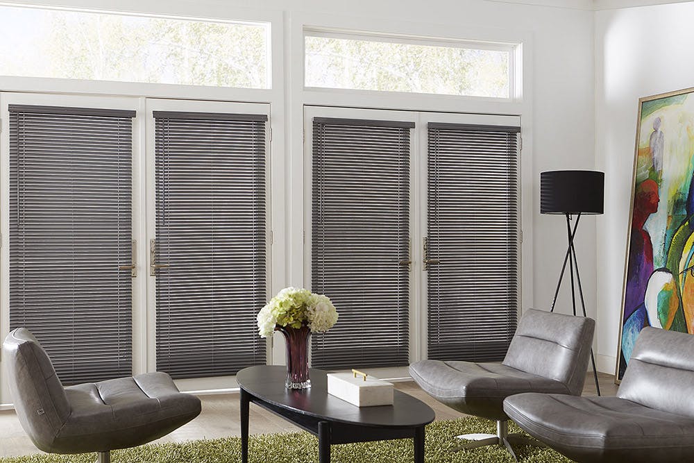  modern living room with three leather chairs and gray mini blinds over the french doors.