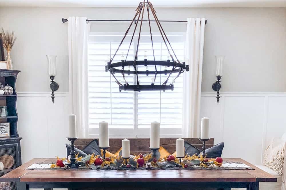 Modern farmhouse dining room decorated for fall with shutters in window.