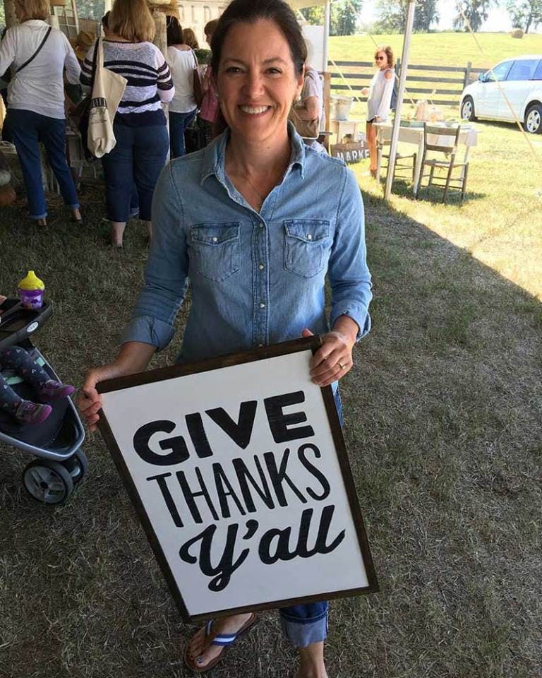 Susie Harris holding “Give thanks y’all” sign