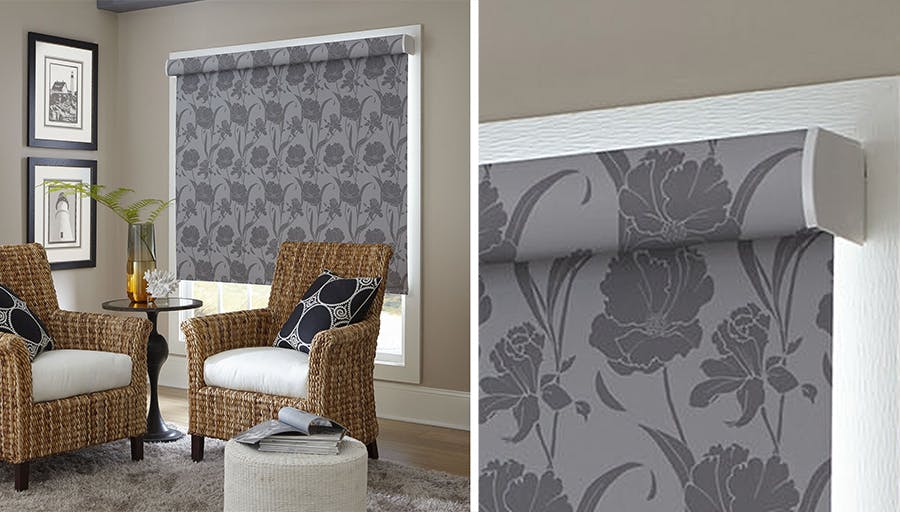 living room corner with two wicker chairs and a grey, floral solar roller shade lowered over the window.