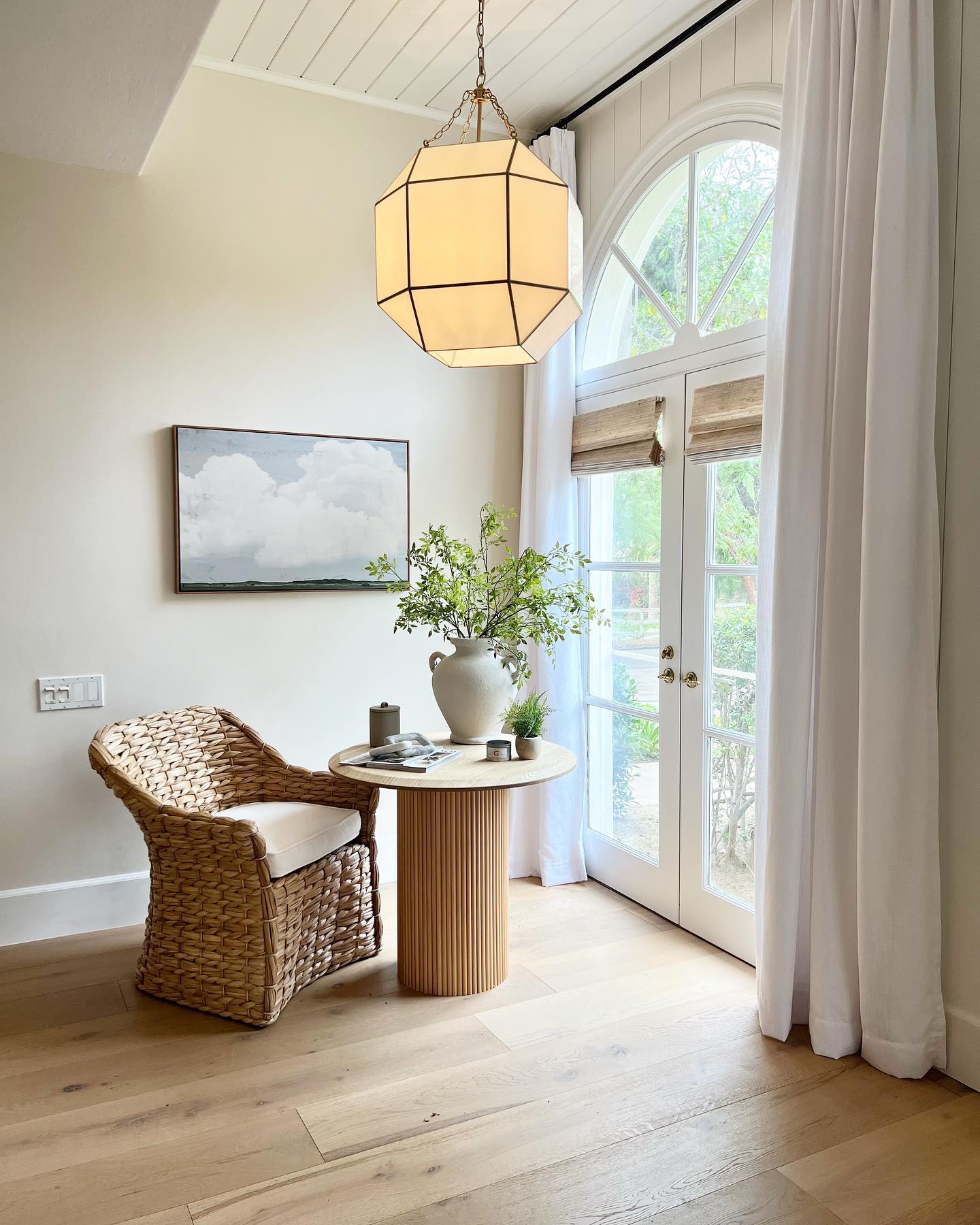 A fall home with a wooden or bamboo table next to a straw chair facing french doors with woven wood shades from Blinds.com.