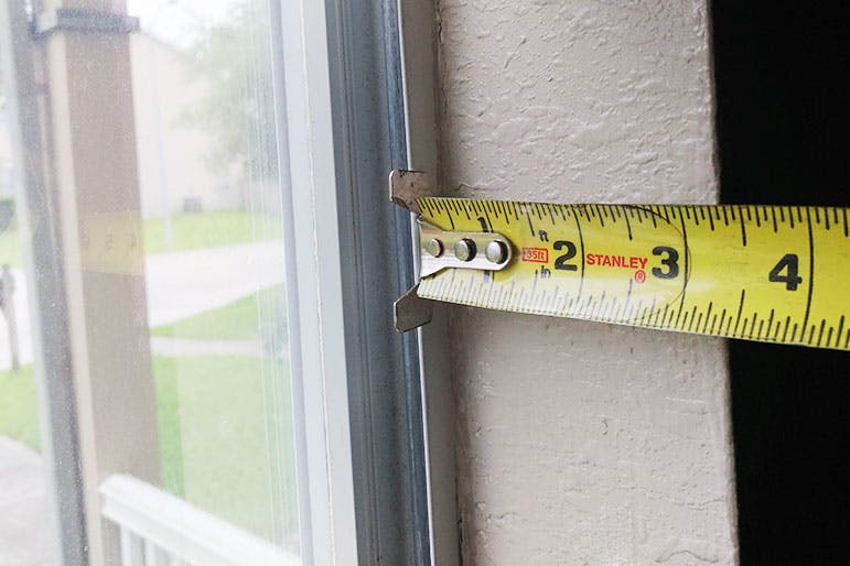 A steel tape measure checking the inside depth of a window frame. 