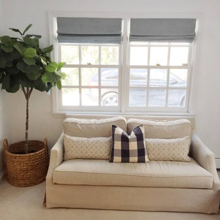 loveseat in front of window with two grey roman shades
