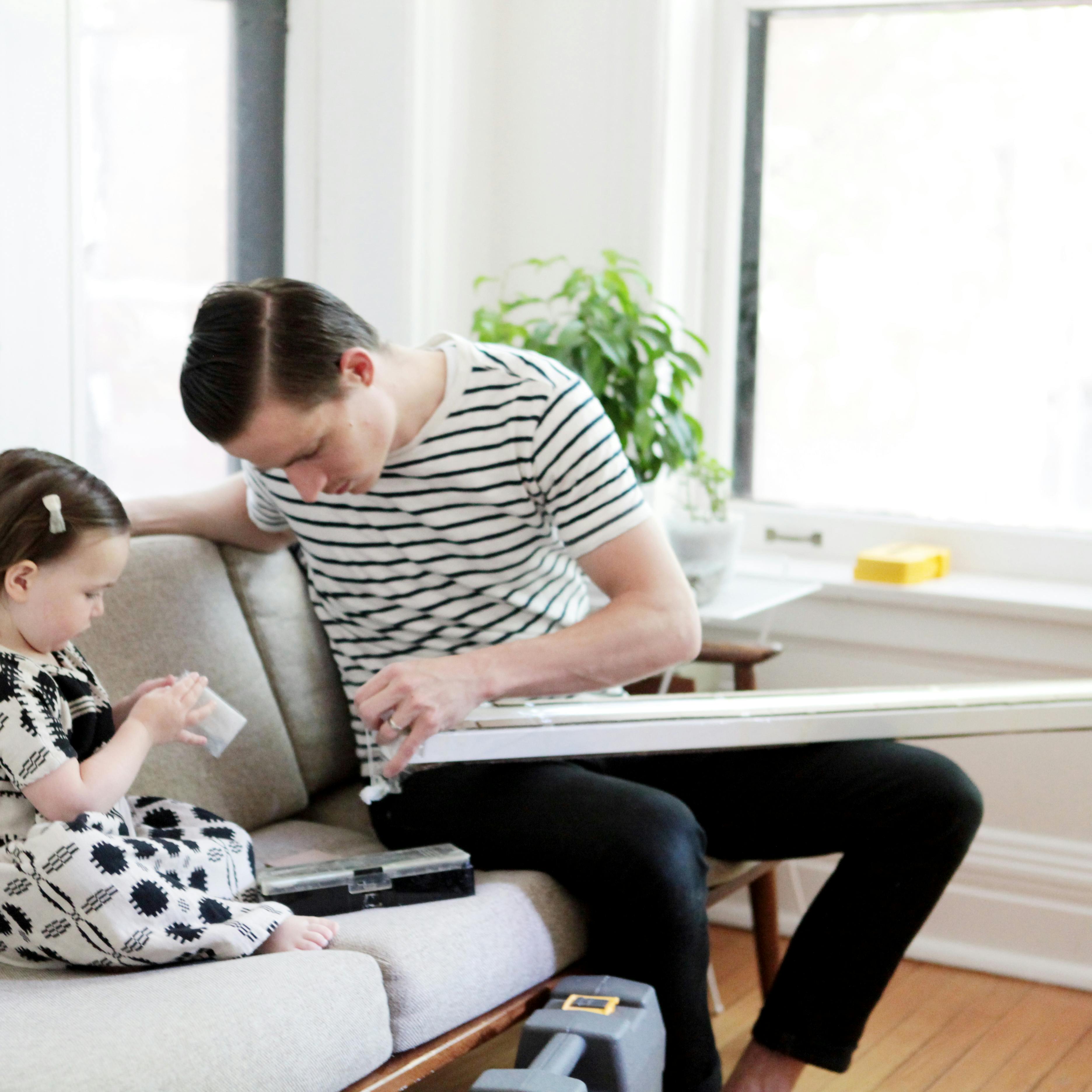 Toddler girl helping dad install blinds