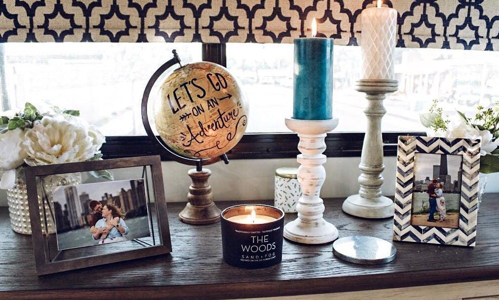 Rustic candles, vases and picture frames with photos of Tiny Home Hailey and Michael on a dark wood display cabinet.