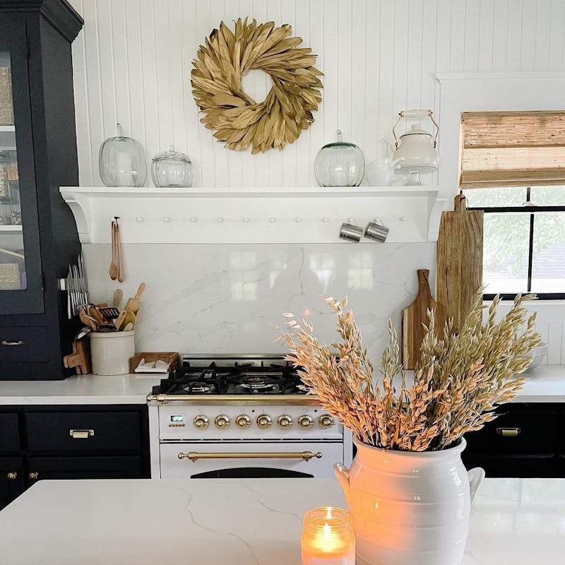 Kitchen decorated for fall with white and gold accents and woven wood shade window coverings from Blinds.com.