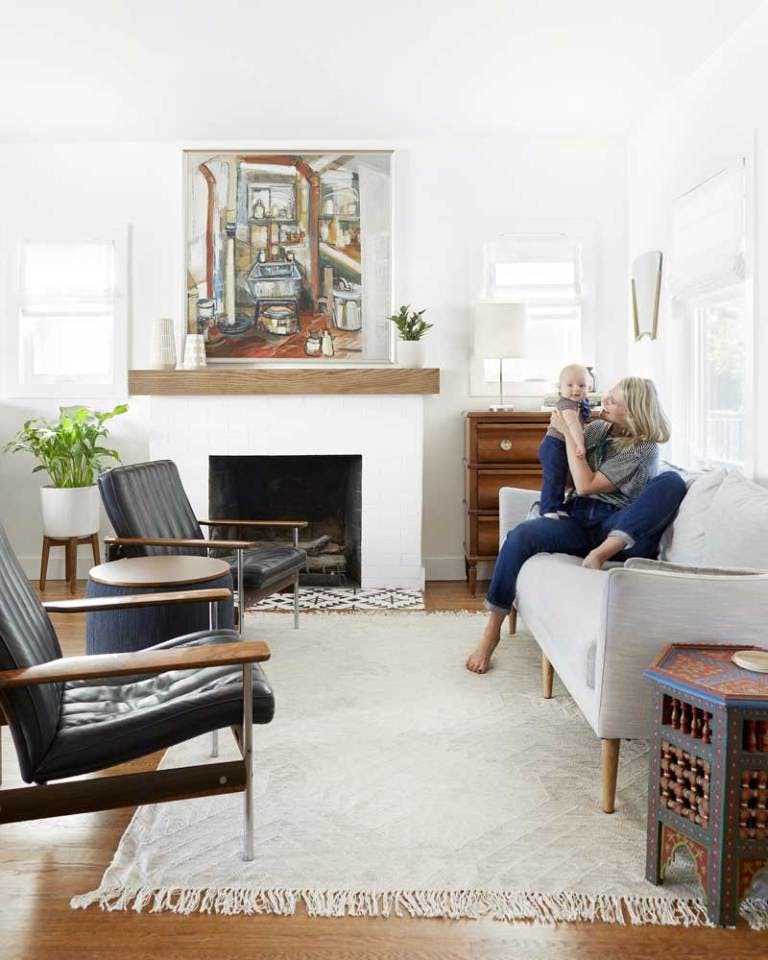 woman in contemporary white living room holding baby on couch