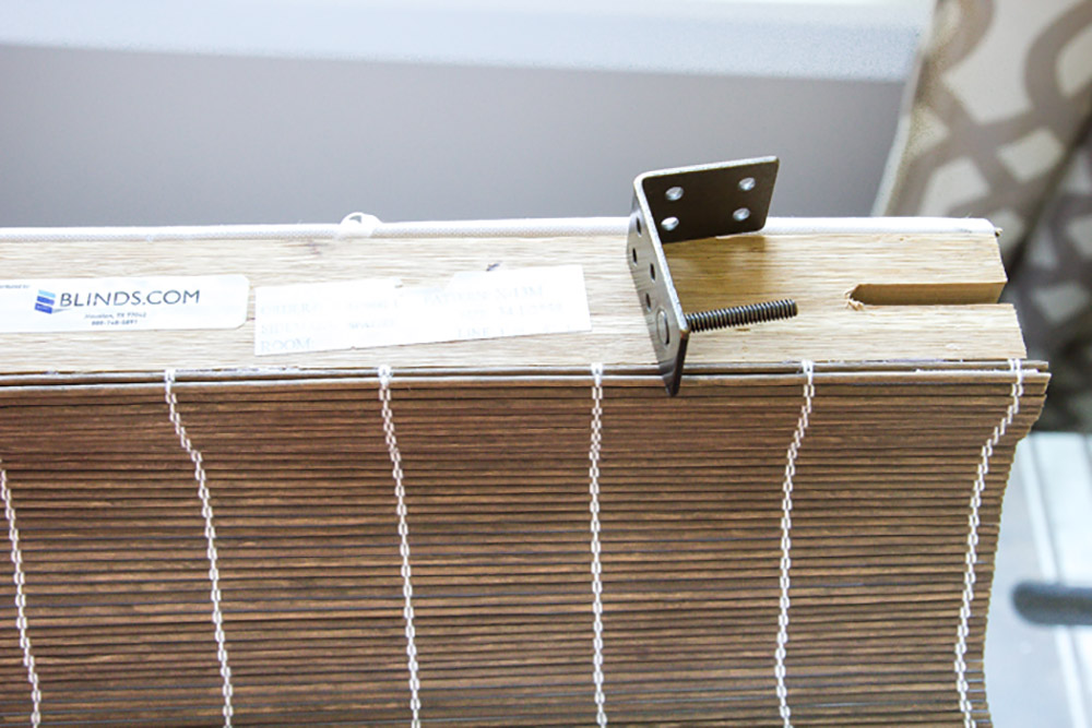 The bracket and headrail of a Blinds.com woven wood shade in the shade Capri Maple.