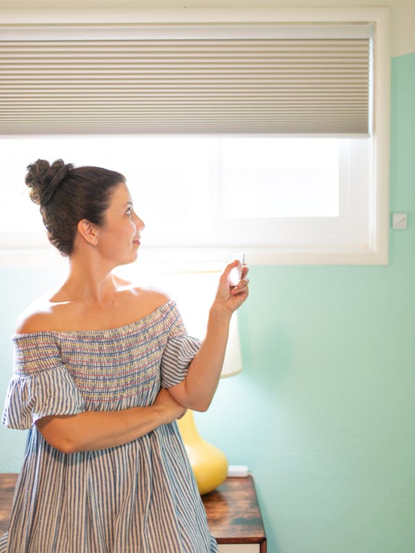 A woman pointing a remote toward her Blinds.com motorized shades