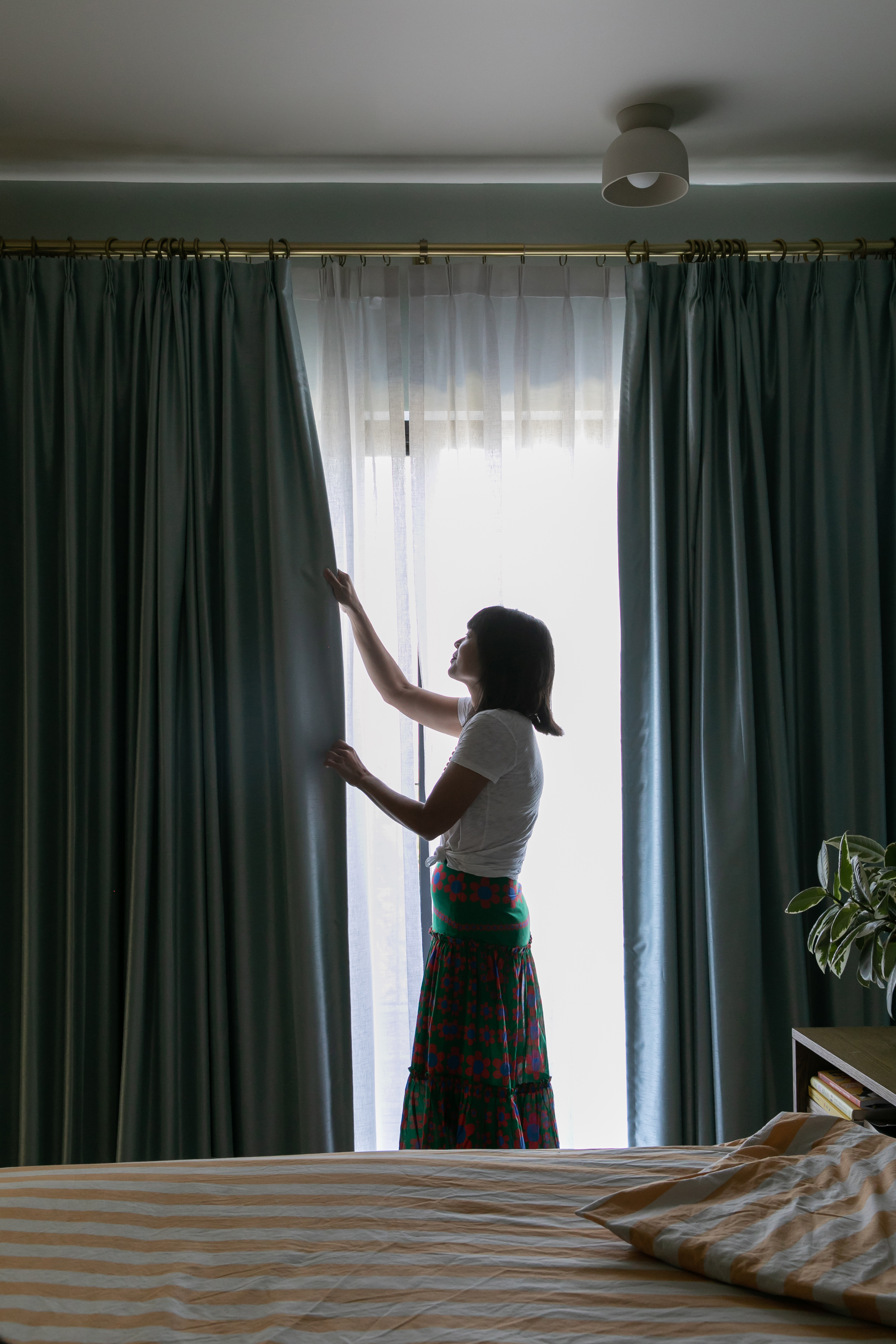 A woman closing her Easy Classic Pleat and French Pleat Drapery in her bedroom.