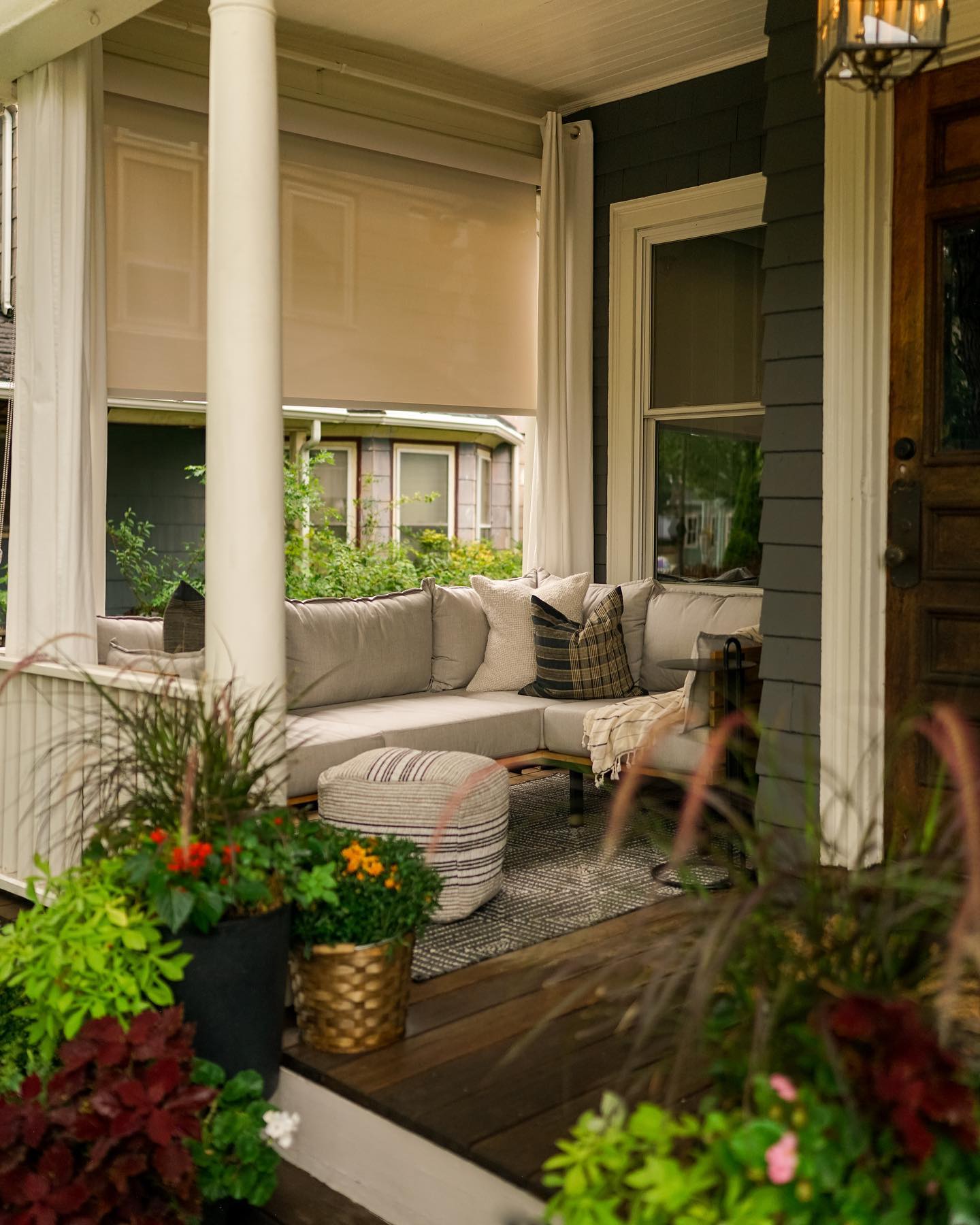 Autumn porch decorated for fall with neutral outdoor seating, beige outdoor solar shades from Blinds.com, and potted plants