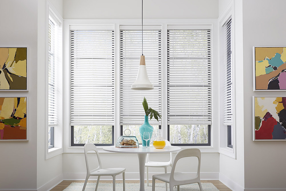 Sunny, white kitchen nook with a small table, two chairs, a pitcher of orange juice and plate of pastries.