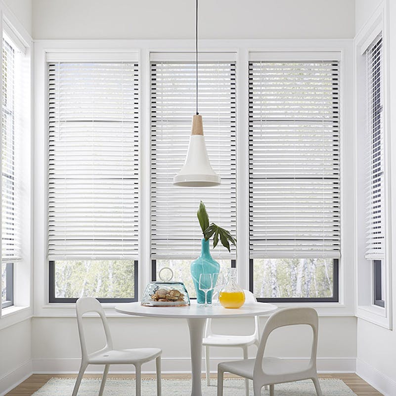 Sunny, white kitchen nook with a small table, two chairs, a pitcher of orange juice and plate of pastries.