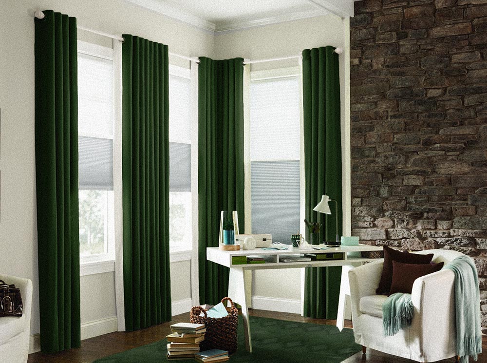 Corner with floor length green velvet draperies, green carpet and a white desk.