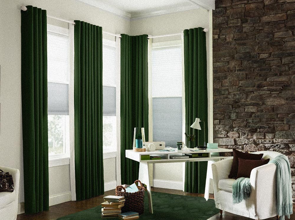 Corner with floor length green velvet draperies, green carpet and a white desk.