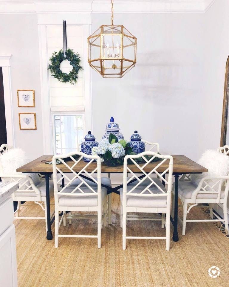 traditional dining room with large wood and wrought iron table, bamboo chairs and white roman shades on window with wreath hanging on top