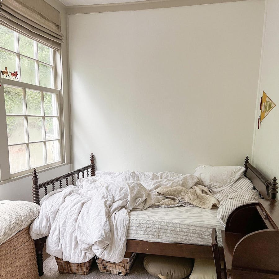 messy bedroom with roman shade window treatments