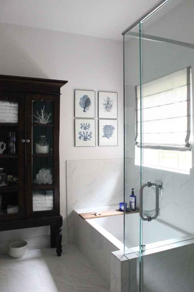 traditional bathroom with dark wood storage cabinet, built-in bathtub and white roman shade with grey ribbon trim on window