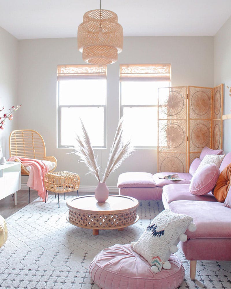 bright white living room with pink furniture and light woven wood shades and wicker accessories.