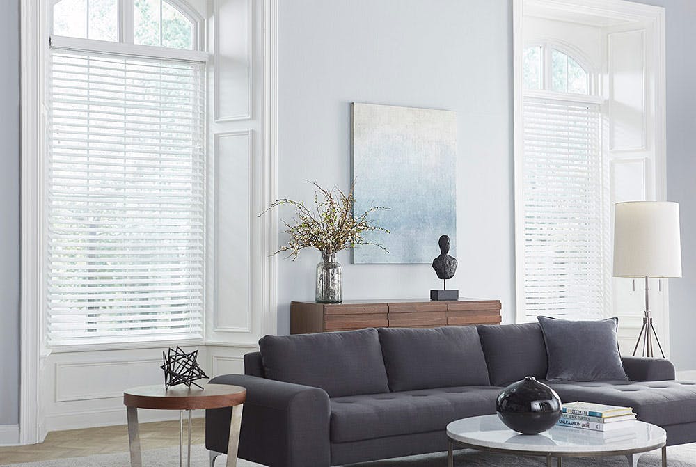 modern living room with white faux wood blinds in large windows.